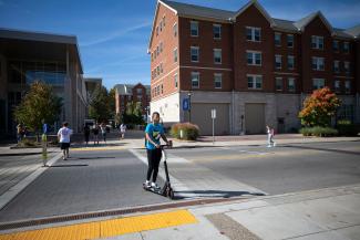 Photo of student riding bird scooter across campus