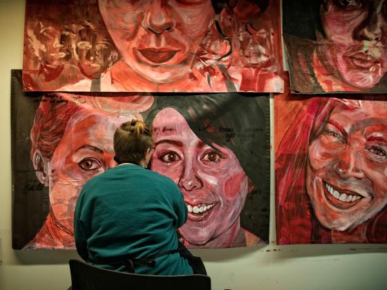 Woman observes portrait paintings in School of Visual Arts and Studies