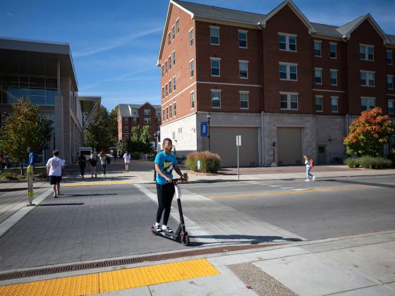 Photo of student riding bird scooter across campus